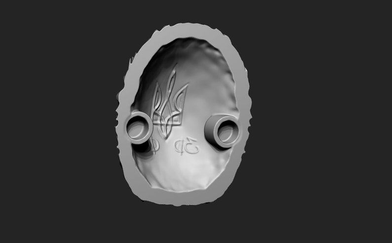 May include: A grey, oval-shaped mould with a raised design of the Ukrainian trident symbol and the letters "ФЕ" in the centre. The mould has two circular holes on the sides.