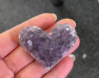 May include: A heart-shaped amethyst crystal cluster with a purple hue. The crystal is made up of many small, pointed crystals that are clustered together.