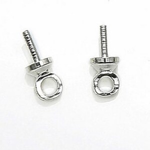 May include: Two silver-toned bead tips with a loop at the top and a small, flat, round base. The bead tips are designed to be used with stringing materials to create jewelry.