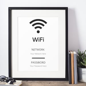 以下が含まれることがあります： 白い背景に黒い枠で囲まれたサイン。サインには、WiFiのシンボル、"WiFi"という単語、"NETWORK"という単語と"Your Network Here"というテキスト、"PASSWORD"という単語と"Your Password Here"というテキストが書かれている。