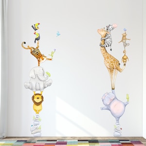 May include: A white wall with a set of animal wall decals. The decals feature a giraffe, a hippopotamus, an elephant, a tiger, a lion, and a toucan. The animals are stacked on top of each other, creating a playful and whimsical scene.