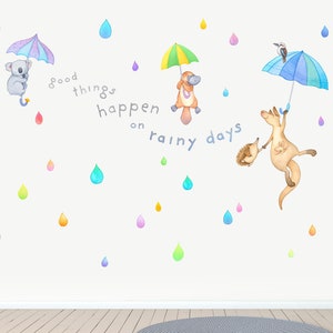 May include: Wall decal featuring a colorful quote, "Good things happen on rainy days", with various animals holding umbrellas, including a koala, a platypus, a kangaroo, and a wombat. The background is white with colorful raindrops.