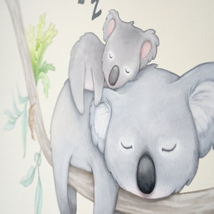 May include: A watercolor illustration of two koalas sleeping on a branch. The larger koala is lying on its back with its arms outstretched, while the smaller koala is curled up on its chest. Both koalas have closed eyes and are depicted in shades of gray.