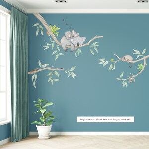 May include: A blue wall with a large koala and joey sleeping on a tree branch. There is a smaller possum on a branch below. The text "Large Koala set shown here with Large Possum set" is at the bottom of the image.