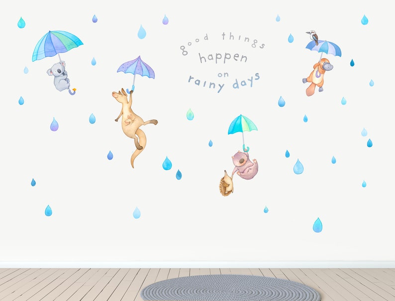 May include: Wall decal featuring a quote about good things happening on rainy days, with illustrations of animals holding umbrellas. The animals include a koala, a kangaroo, a platypus, and a echidna. The quote reads "good things happen on rainy days".