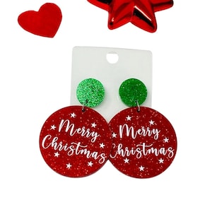 Puede incluir: Pendientes de Navidad de purpurina roja y verde con las palabras "Merry Christmas" en cada pendiente.