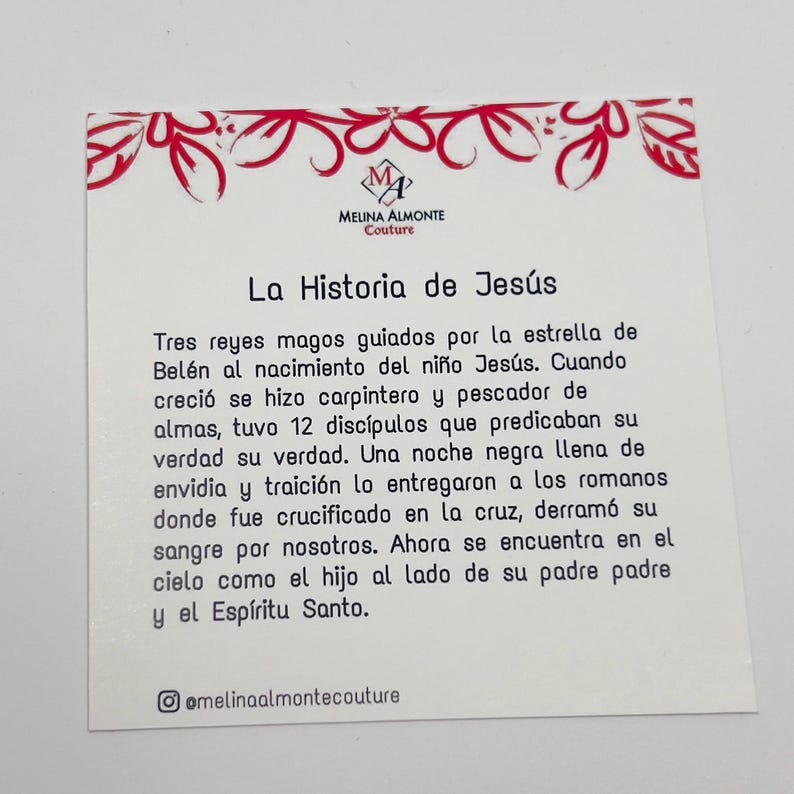 May include: A white card with red floral border and a black and white image of a star. The text on the card reads "La Historia de Jes&uacute;s" and tells the story of Jesus' life. The card also includes the social media handle "@melinaalmontecouture".
