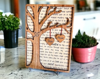 Puede incluir: Un árbol de madera recortado con una abertura en forma de corazón en la parte superior. El árbol está decorado con dos pequeños corazones de madera con los nombres "Jorge" y "Paola" escritos en ellos. El árbol está rodeado de un mensaje escrito a mano sobre el amor y las imperfecciones.