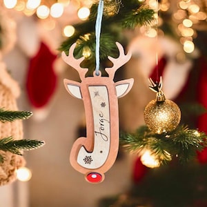 May include: A wooden reindeer Christmas ornament with a red nose and the name "Jorge" engraved on it. The ornament is hanging on a Christmas tree.
