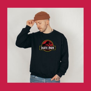 May include: Black sweatshirt with a red and yellow graphic of a dinosaur with the text "Skate Park".