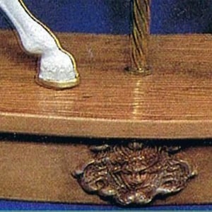 May include: A wooden base with a curved top and a decorative design on the front. The base is painted brown and has a light wood grain texture.