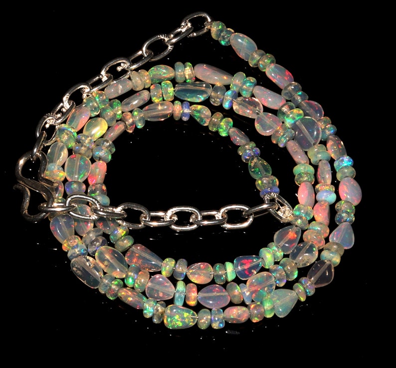 May include: A multi-strand necklace made of iridescent opal beads with a silver chain clasp.