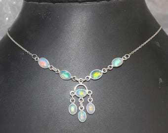 May include: A silver necklace with a pendant featuring a cluster of iridescent opal stones. The necklace has a delicate chain and a simple design.