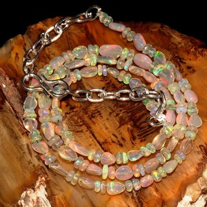 May include: A multi-strand necklace made of iridescent opal beads in various shapes and sizes. The necklace is secured with a silver clasp and chain.