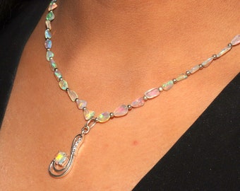 May include: A silver necklace with a pendant featuring a white opal gemstone. The necklace is made of small, teardrop-shaped opal beads.