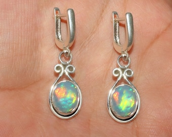 May include: A pair of silver dangle earrings with opal gemstones. The opals are iridescent with shades of green, blue, and orange.