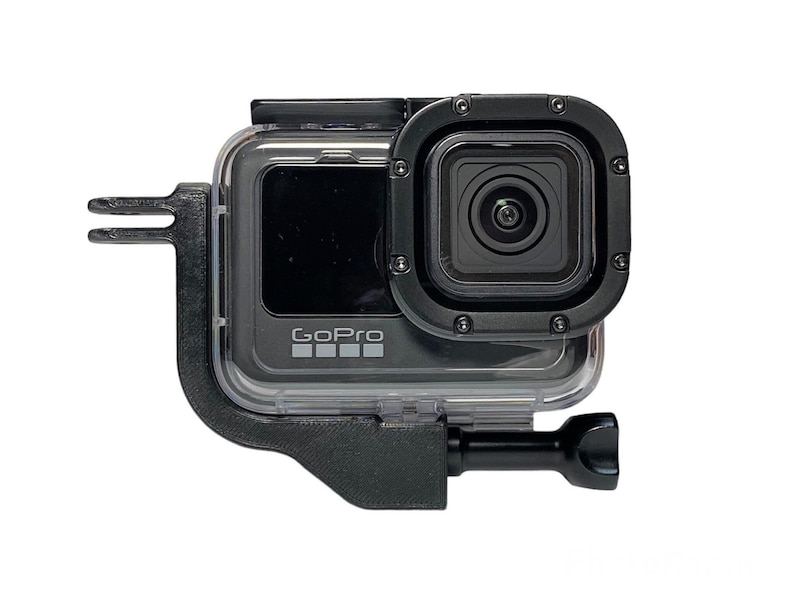May include: A black GoPro camera with a clear protective case and a black mount. The camera has a black lens and a GoPro logo on the front.