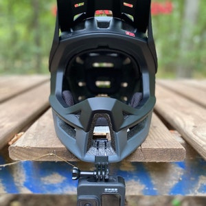 Puede incluir: Un casco integral negro con visera y una c&aacute;mara GoPro fijada en la parte inferior.
