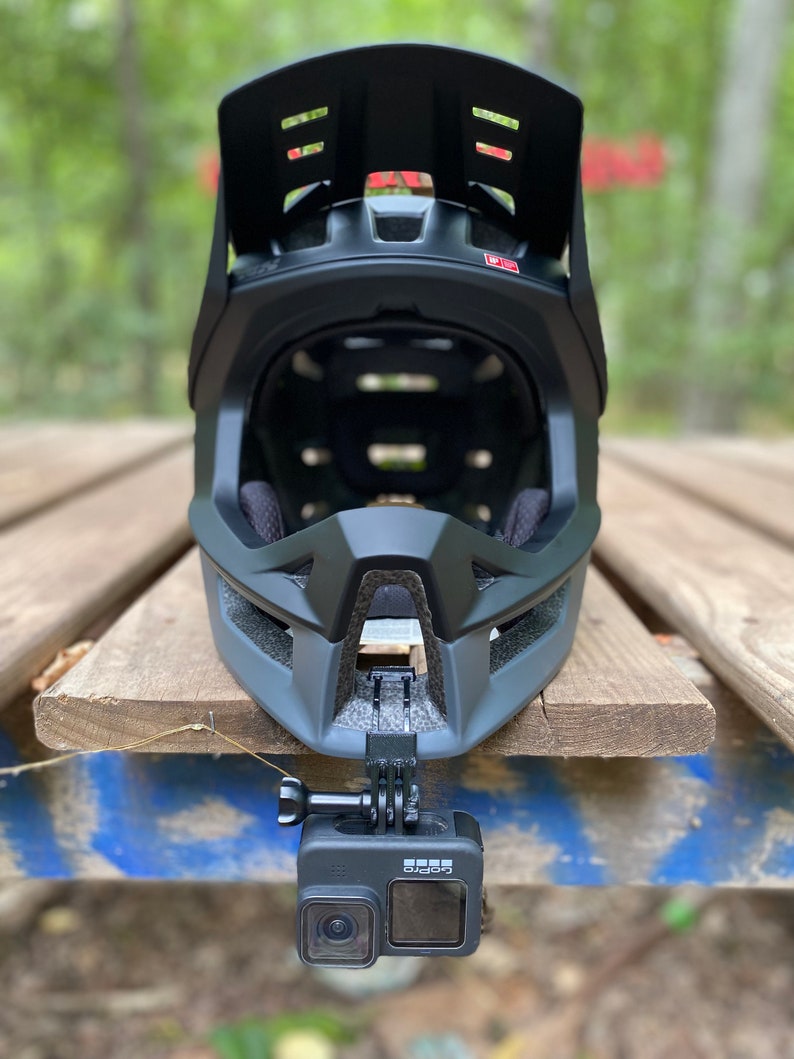 Puede incluir: Un casco integral negro con visera y una c&aacute;mara GoPro fijada en la parte inferior.