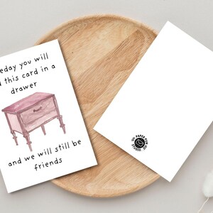 Peut inclure: Deux cartes de v&oelig;ux blanches sur un plateau en bois. L'une d'elles pr&eacute;sente une illustration &agrave; l'aquarelle d'une petite commode et le texte "someday you will find this card in a drawer and we will still be friends."