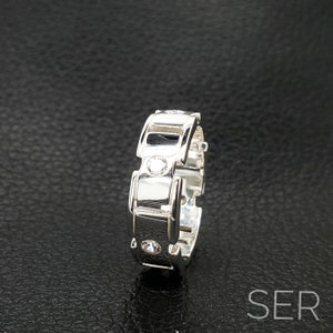 May include: A silver ring with a unique design featuring multiple small clear stones.