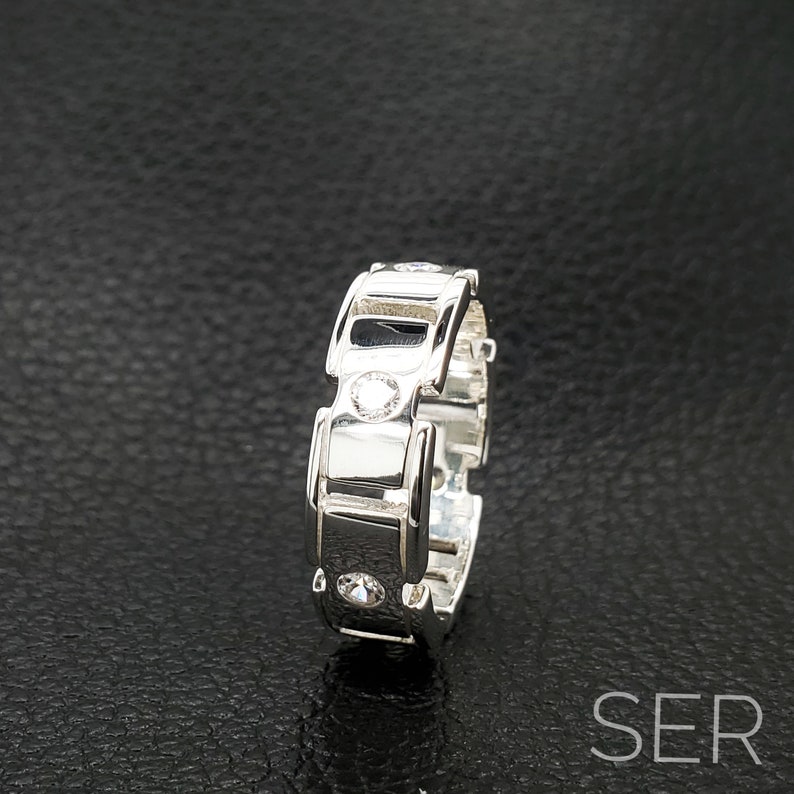 May include: A silver ring with a unique design featuring multiple small clear stones.