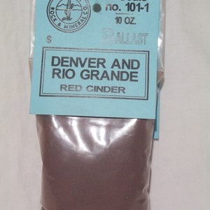 Puede incluir: Una bolsa de balasto de ceniza roja para modelismo ferroviario. La bolsa está etiquetada con "Denver and Rio Grande" y "N Scale no. 101-1".