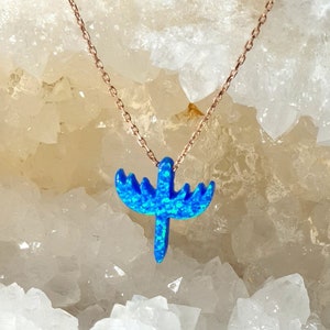 Op de afbeelding: Een ketting met een roségouden ketting en een blauwe opaal hanger. De hanger heeft een unieke vorm en is helderblauw. De ketting wordt gepresenteerd op een wit, kristalachtig oppervlak. De ketting is delicaat.