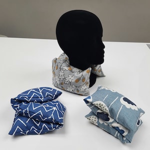 Puede incluir: Tres almohadas de cuello de tela, una con un patr&oacute;n de chevron azul y blanco, otra con un patr&oacute;n floral azul y blanco y otra con un patr&oacute;n de bellota gris y blanco.