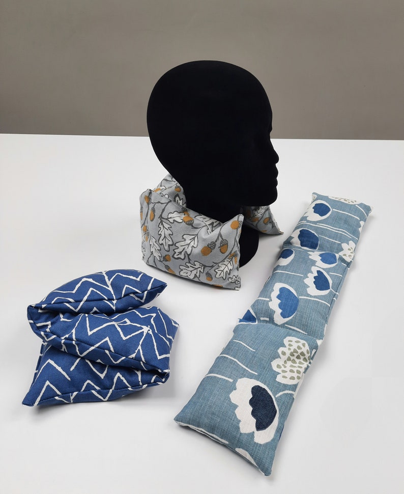 Puede incluir: Tres paquetes de calor cubiertos de tela diferentes. Uno es de forma larga y rectangular con un patr&oacute;n floral azul y blanco. Otro es de forma rectangular m&aacute;s peque&ntilde;a con un patr&oacute;n de chevron azul y blanco. El tercero es de forma rectangular m&aacute;s peque&ntilde;a con un patr&oacute;n gris y blanco de hojas de roble y bellotas.