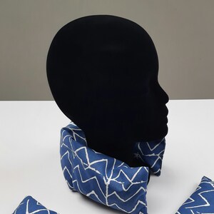 Puede incluir: Almohada de cuello azul y blanco con un dise&ntilde;o en zigzag. La almohada est&aacute; en una cabeza de maniqu&iacute;.