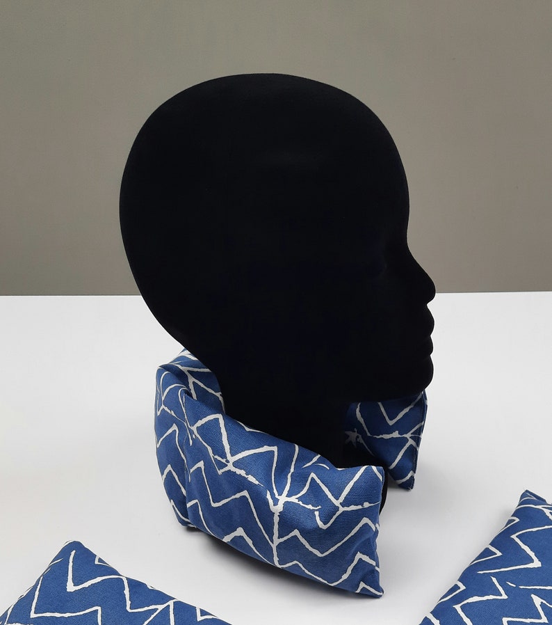 Puede incluir: Almohada de cuello azul y blanco con un dise&ntilde;o en zigzag. La almohada est&aacute; en una cabeza de maniqu&iacute;.