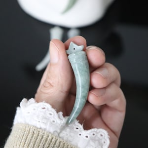 May include: A green jade pendant carved in the shape of a tooth with a small star on top.