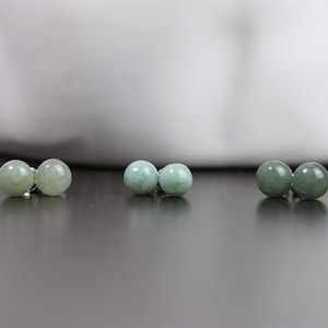 May include: Three pairs of jade green stud earrings. Each pair features two round jade stones.