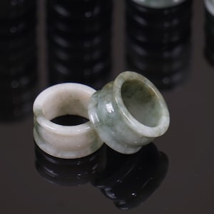 May include: Two jade rings, one green and one white, with a smooth, polished finish. The rings are stacked on top of each other.