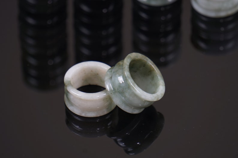 May include: Two jade rings, one green and one white, with a smooth, polished finish. The rings are stacked on top of each other.