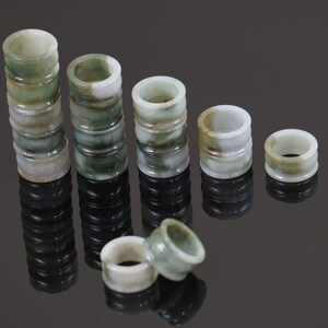 May include: A set of jade rings stacked in decreasing size, with the largest stack being 10 rings high. The rings are a mottled green and white colour.
