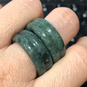 May include: Two jade green rings stacked on a finger. The rings are smooth and have a slightly rounded shape.