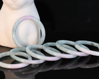 May include: A set of eight jade bangles in shades of green and pink. The bangles are stacked on top of each other, creating a visually appealing display.