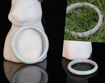 May include: A light green jade bangle bracelet with a smooth, polished finish.