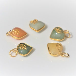 May include: Four heart-shaped pendants with gold accents and different colored stones. The stones are green, light green, pink, and yellow.