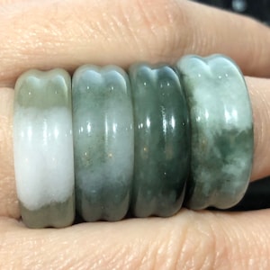 May include: Set of five jade rings in various shades of green and white. The rings are smooth and polished, with a slightly rounded shape.