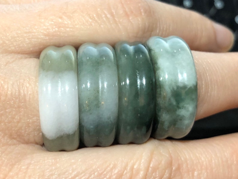May include: Set of five jade rings in various shades of green and white. The rings are smooth and polished, with a slightly rounded shape.