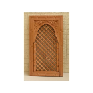 May include: A wooden decorative wall panel with an intricate carved design. The panel features an arched opening with a lattice pattern and floral accents.