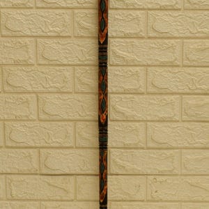 Puede incluir: Bast&oacute;n decorativo con acabado marr&oacute;n oscuro. El bast&oacute;n presenta intrincados dise&ntilde;os en naranja, verde y turquesa. La parte superior tiene un dise&ntilde;o redondeado y estampado. El bast&oacute;n est&aacute; contra una pared de ladrillos texturizada de color blanquecino.