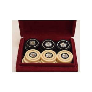 May include: A set of black and white game pieces with intricate inlaid designs in a red velvet lined box.