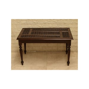 May include: A dark brown wooden table with a rectangular top and carved details. The table has four turned legs and a decorative pattern in the center. The table is approximately 48 inches long and 24 inches wide.