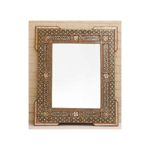 Può includere: Uno specchio da parete rettangolare con una cornice complessa intarsiata in madreperla e legno scuro. La cornice presenta motivi geometrici, disegni a stella e piccoli accenti quadrati, creando un bordo dettagliato attorno al vetro.