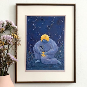 Op de afbeelding: Ingelijste kunstdruk met een zittende blauwe figuur met een gele kop, die een gouden ster vasthoudt. Het kunstwerk is geplaatst tegen een donkerblauwe sterrenhemel. De print zit in een bruine houten lijst, met een witte passe-partout. Het kunstwerk wordt op een witte muur getoond.