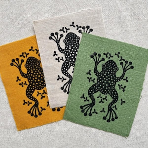 Parche de lino hecho a mano con estampado en linóleo de una rana. Remiendo visible.